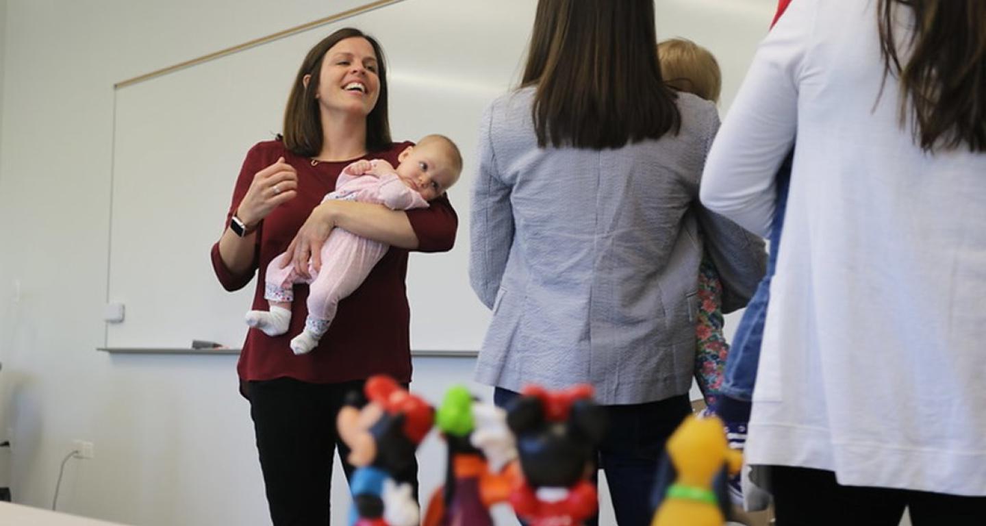 person holding baby in front of students